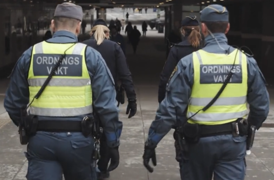 Två ordningsvakter med ryggen mot bilden går igenom en tunnel på Resecentrum i Uppsala