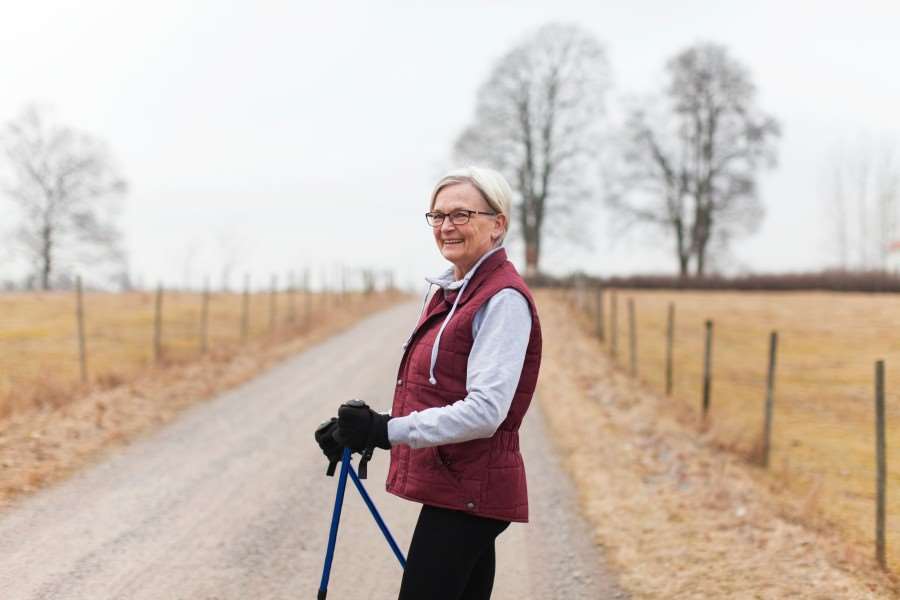 Äldre kvinna som går en promenad med stavar