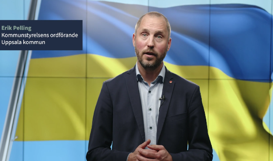 Erik Pelling står framför en stor digital tavla som visar Ukrainas flagga