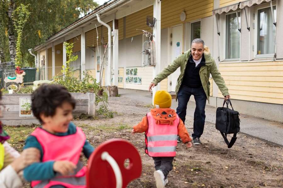 Glad pappa hämtar barn på förskolan.