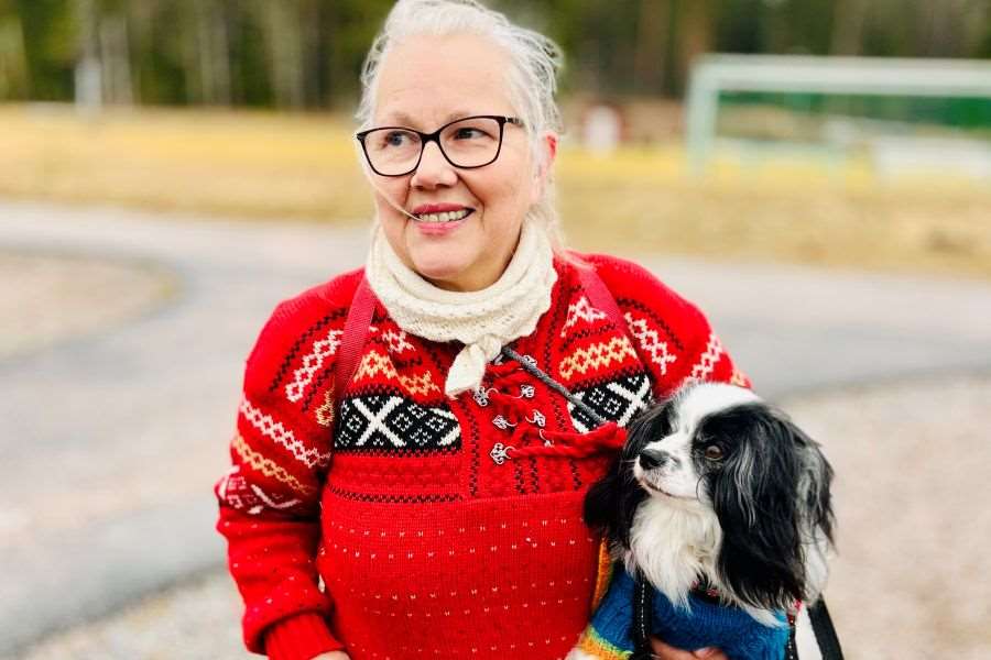 Kvinna i röd tröja med en hund i famnen.