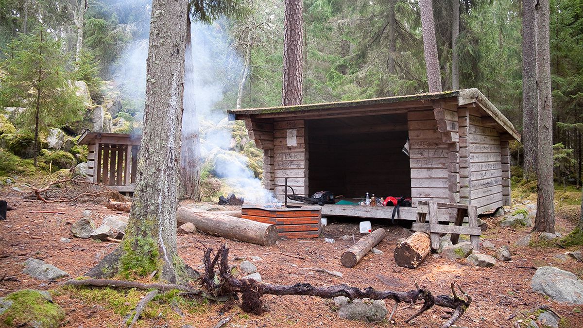 Ett vindskydd och en grillplats där någon eldar i Storskogens friluftsområde.