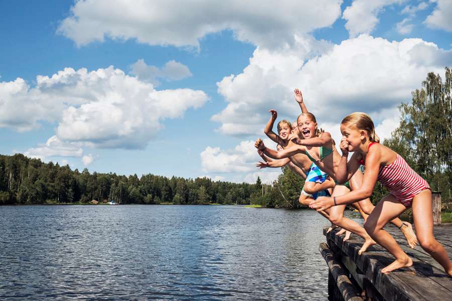 Barn hoppar ner i en sjö på sommaren